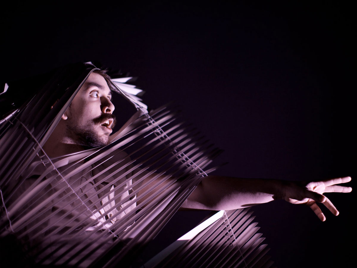 Fuschia Future. The image shows a man looking and reaching through a Venetian blind. There's a light purple spotlight on him.
