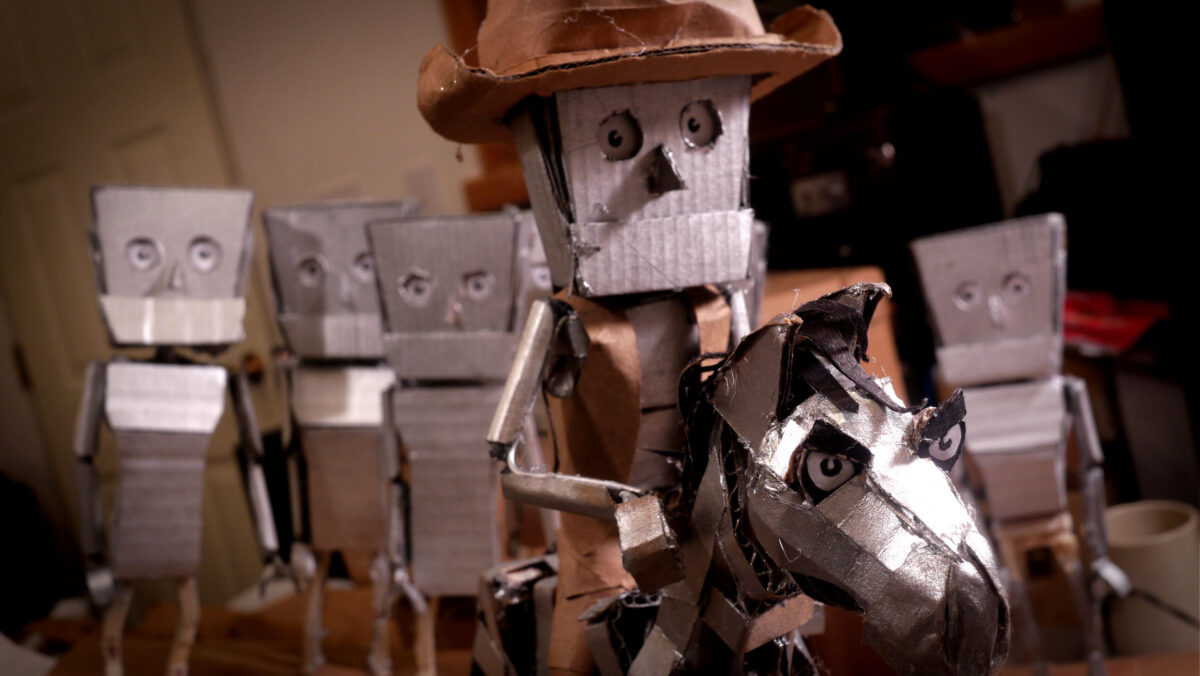 The image shows a collection of handmade robots inside a room. The one in the front is riding a horse and wearing a cowboy hat.