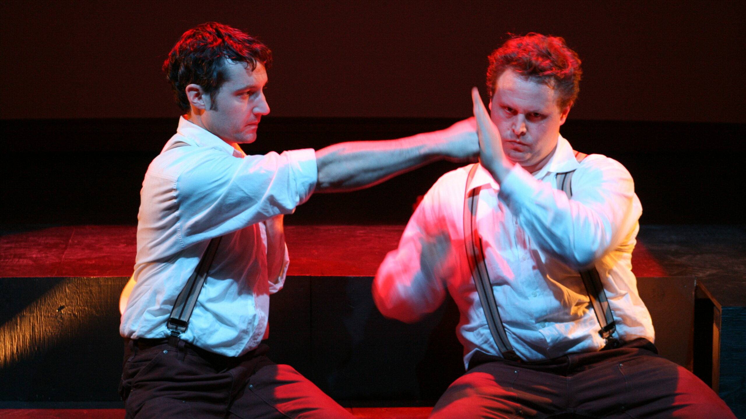 A man punching another on a red stage.