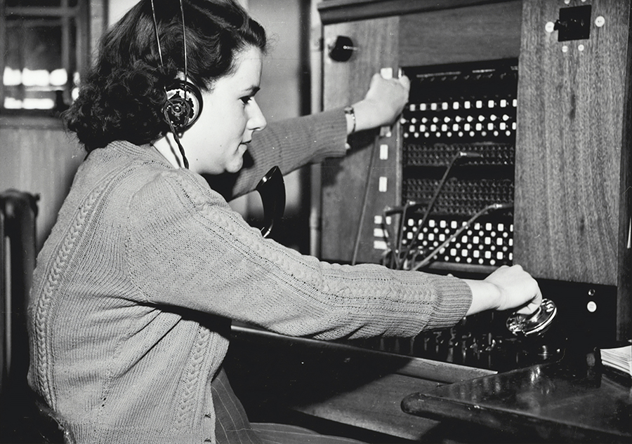 A 50s era operator connects wires to place phone calls
