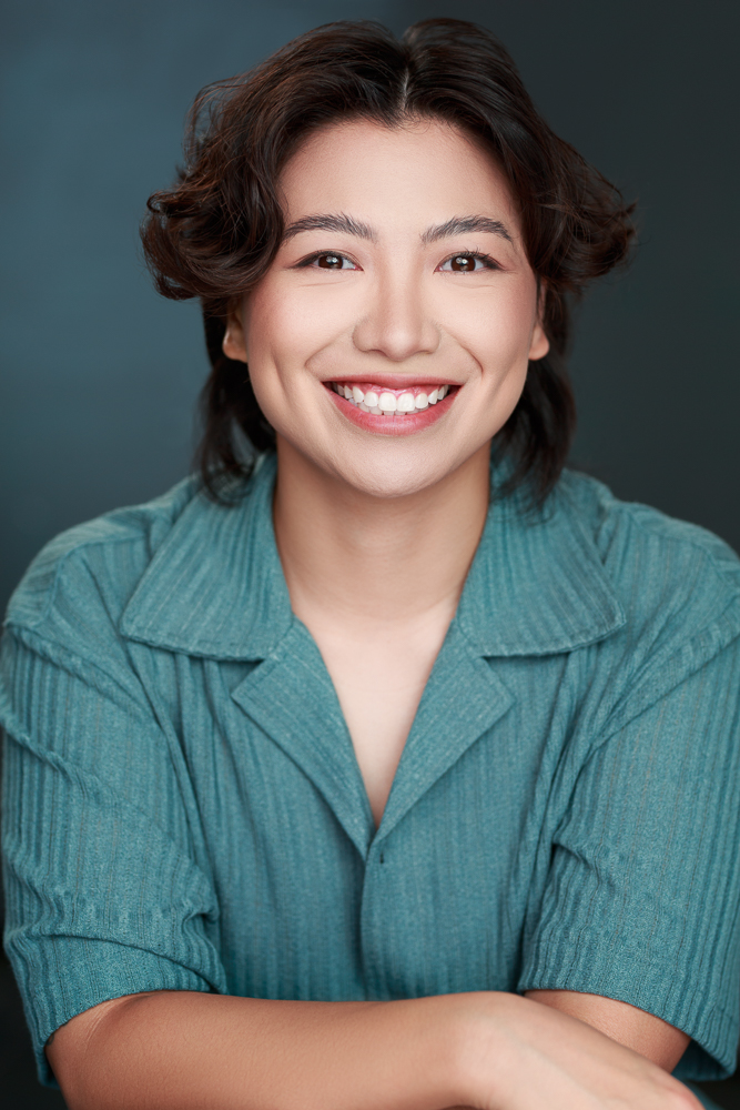 Headshot of a Filipinx-Canadian person with short brown hair and a teal collared shirt smiling at the camera.